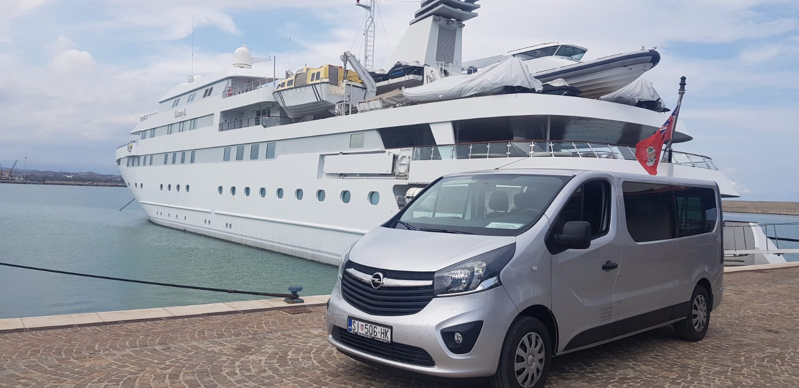 Cipollina silver shuttle van parked directly on the quay beside a moored superyacht — direct pontoon access without waiting